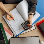 Een laptop en notitieboek met financiële documenten en kaarten voor het beheren van zakelijke financiën.